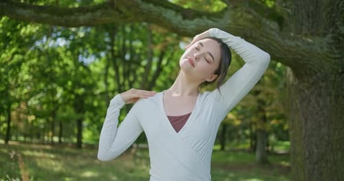Young Beautiful Athletic Woman in Sportswear Doing Stretching and Warming Up in the Park Near a Tree