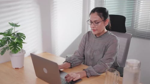 Asian woman working and using laptop at home or office Look at the computer screen