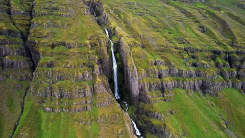 Aerial view of a small waterfall along the mountain crest in Iceland.