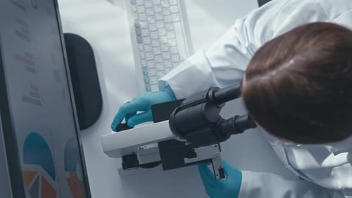 Scientist Using Microscope and Computer in Lab
