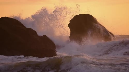 Enormes ondas turbulentas batendo entre enormes formações rochosas e engolindo pequenas rochas durante