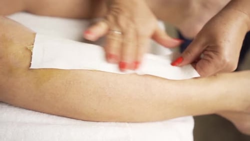 Nahaufnahme weiblicher Beine Haarentfernung mit Wachs im Schönheitssalon. Zeitlupe