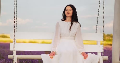 a Girl in a White Light Dress Swings on a Swing in a Lavender Field