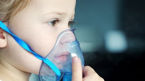 Close Up View of Little Girl are Sitting and Holding a Nebulizer Mask Leaning Against the Face