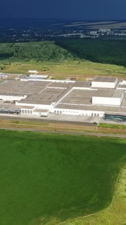 Aerial view from afar on manufacturing complex. Large industrial territory surrounded by green field