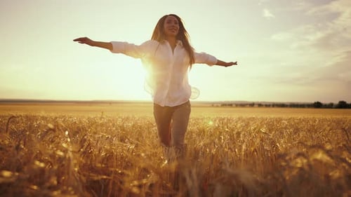 Romantic Carefree Happy Woman Running on Yellow Wheat Field with Spreading Flying Arms Enjoying