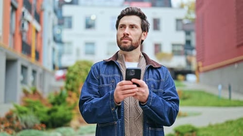 Man Looks Happy While Messaging on Mobile Phone in City