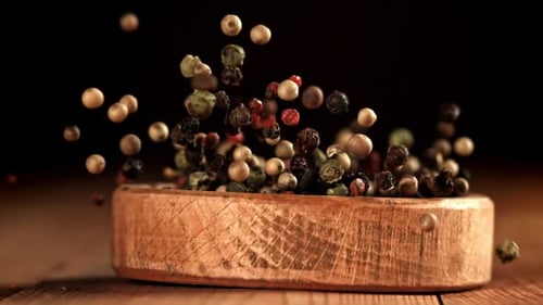 Wooden Bowl with Mixed Peppercorns Falling in Slow Motion