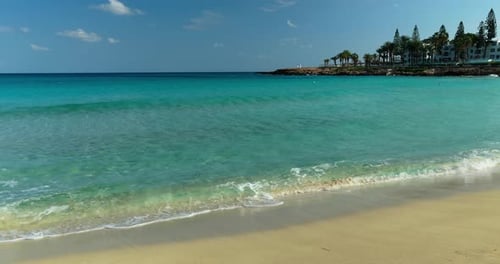 Ground level view of clear turquoise sea with gentle waves at sandy beach in Protaras