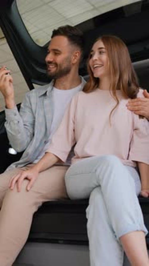 Happy Couple Showing Keys to New Car in Dealership
