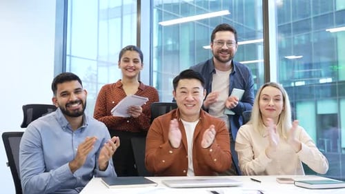 Group of business corporate people applauding look at camera sitting at workplace in office