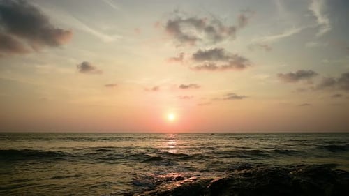 Dramatic sunset with orange sky in a cloudy day at a tropical beach.