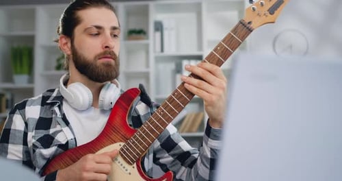 Man Plays Electric Guitar in Brightly Lit Room