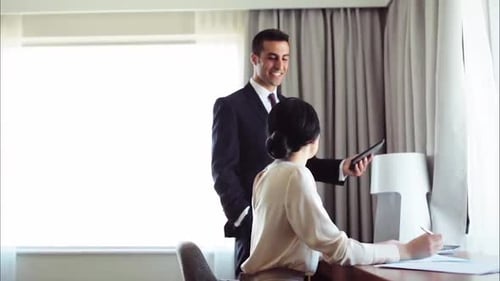 Happy hispanic business team talks work with tablet and papers in hotel room