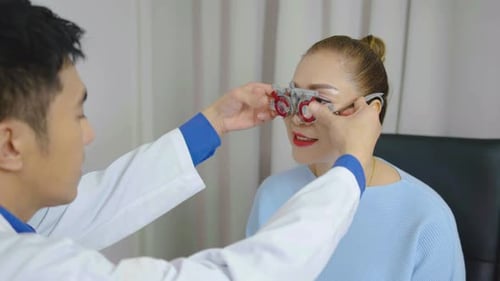 Lächelnde Seniorin überprüft während einer ärztlichen Untersuchung ihr Sehvermögen mit einer Sehtestbrille