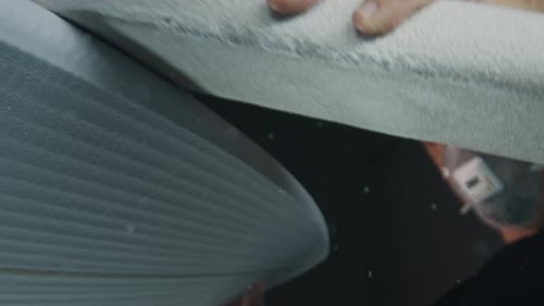 Surf board factory. Adult male shaper creates the surfing board on the factory