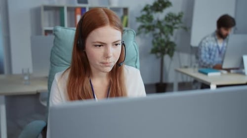 Une femme concentrée travaille intensément sur son ordinateur portable dans un espace de travail moderne