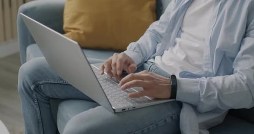 Man Typing on Laptop While Relaxing on Couch