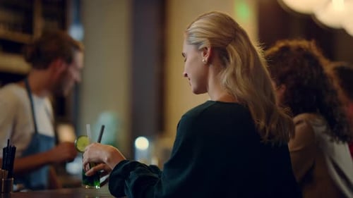 Gorgeous Woman Sitting At Bar Counter With Cocktail. Handsome Bartender Talking With Beautiful Vi...