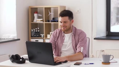 Man Working on Laptop Expressing Success at Home
