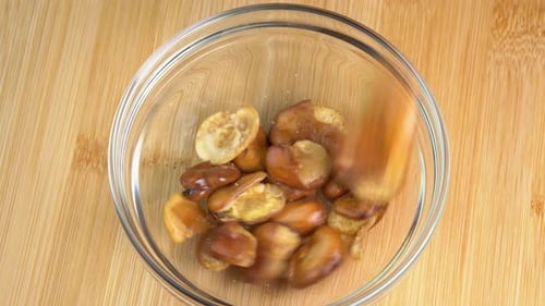 Fried broad bean pouring in glass bowl. Salty roasted broad bean beer snack, snack food macro