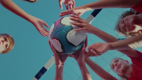 Spieler der Jugendfußballmannschaft stehen im Kreis und halten den Ball gegen das Fußballtor und den Himmel