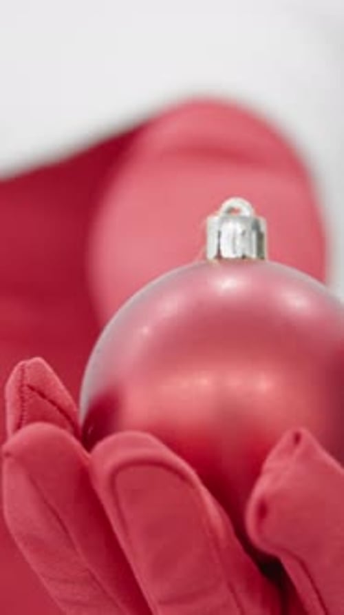 Red Christmas Ball Held by Person in Red Outfit