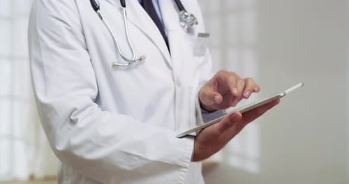 4k video of a young male doctor using a digital tablet in a hospital