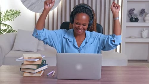 Woman Listening to Music and Using Laptop at Desk