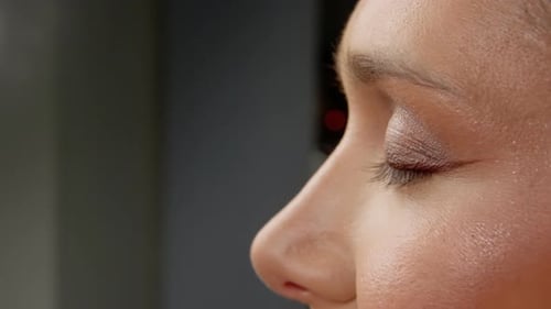 Artista de maquillaje profesional que aplica cuidadosamente pestañas postizas en el párpado de la modelo durante el salón de belleza