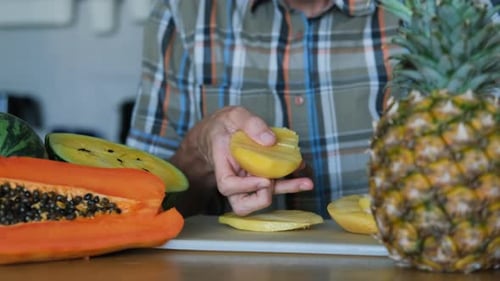 Cutting a Mango into Pieces on White Cutting Board