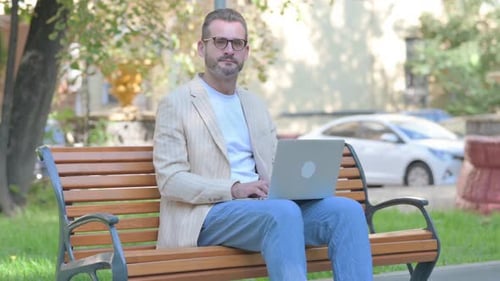 Man Working on Laptop in Urban Park Setting