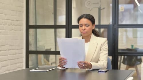 Professional Woman Reviews Documents at Office Desk