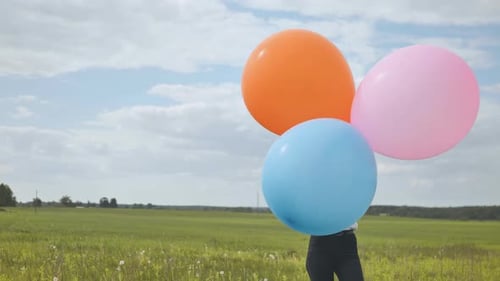Happy Girl with Big Multicolored Balloons Posing on the Field