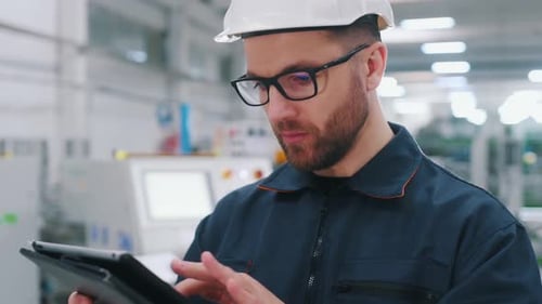 Tablett in der Hand Der Fabrikarbeiter ist mit Schutzhelm drinnen.