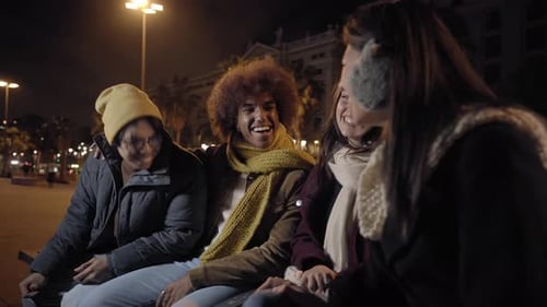 Generation z Friends Chatting and Laughing Sitting in City Square at Night Group of Excited People