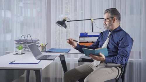 Elderly businessman working in office using laptop.