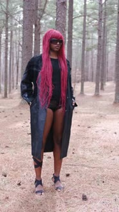 Stylish Black Woman with Pink Hair Posing in a Forest