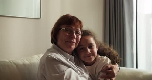 Close Up of Loving Elderly Grandmother Hugs Little Granddaughter 30s Granddaughter Family Sit on