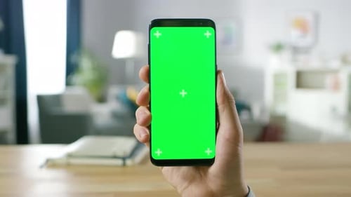Close-up of a Man Holding Green Mock-up Screen Smartphone and Using Touchscreen Gestures. Touching
