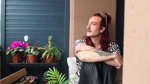 Young non-binary person relaxing on balcony with plants