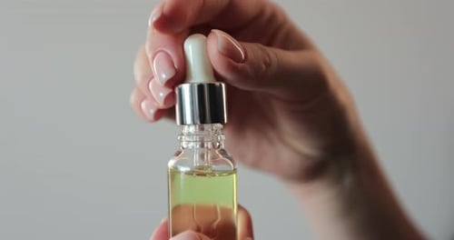 Woman Drips Oil into Bottle with Dropper