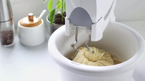 A stationary mixer with a bowl kneads the dough in slow motion.