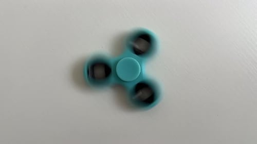 Blaues Fidget Spinner-Spielzeuggerät, das sich auf dem Tisch dreht