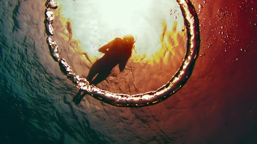 Woman swims in the sea. Bottom view of the person snorkeling on the surface and bubble ring