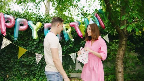 Woman Receives Birthday Gift from Friend Outdoors