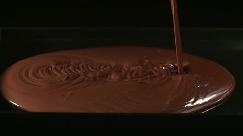 Mélanger des cubes de chocolat avec de la poudre de cacao fine, sur fond noir, mélanger avec un bol en argent
