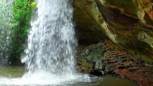 Scenic waterfall emerges from hidden cave.