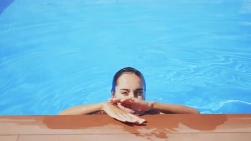Woman Relaxing on Edge of Swimming Pool on Sunny Day