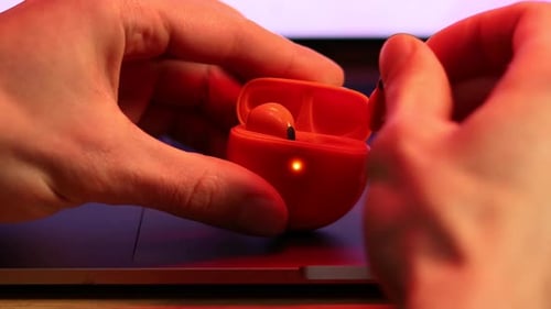 Opening Orange Wireless Earbud Case on Laptop